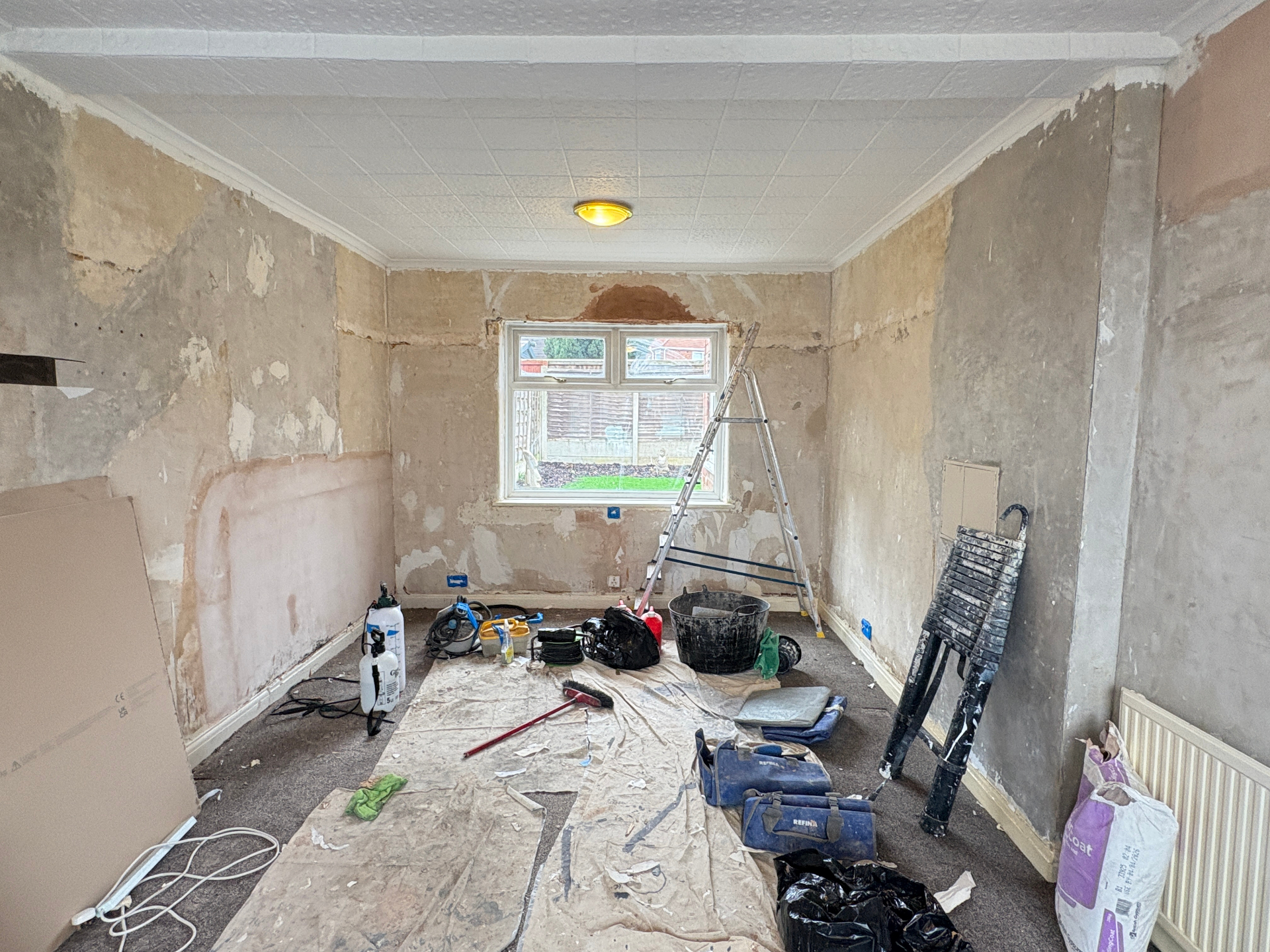 Living room before — stripped walls ready for plastering